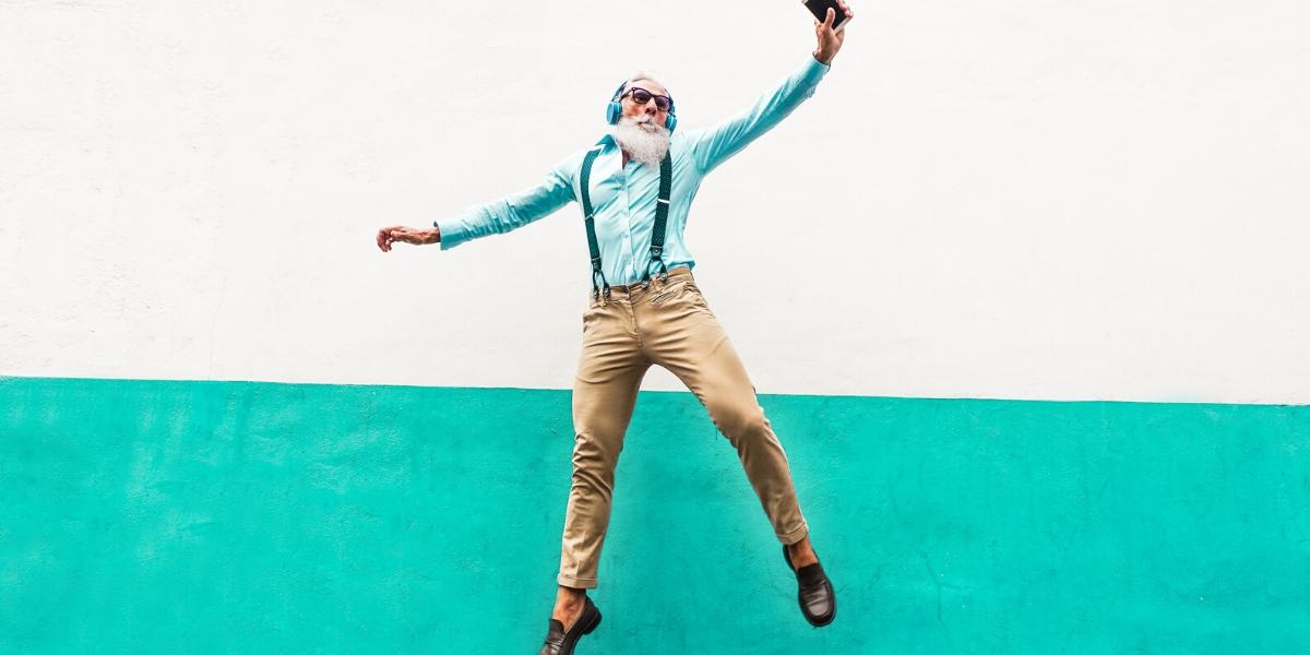 A senior man dancing and listening to music on headphones while participating in one of Cano Health's senior wellness programs