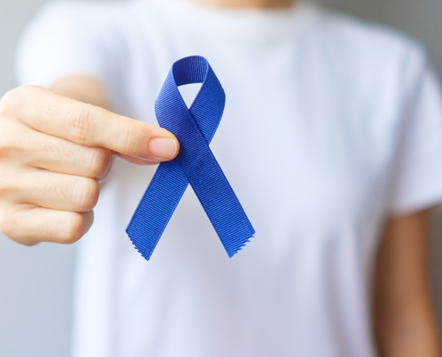 Photo of a person holding a blue ribbon for March Colorectal Cancer Awareness month