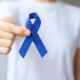 Photo of a person holding a blue ribbon for March Colorectal Cancer Awareness month