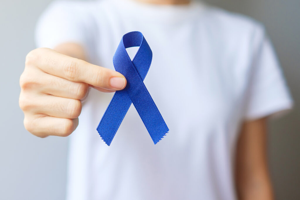 Photo of a person holding a blue ribbon for March Colorectal Cancer Awareness month