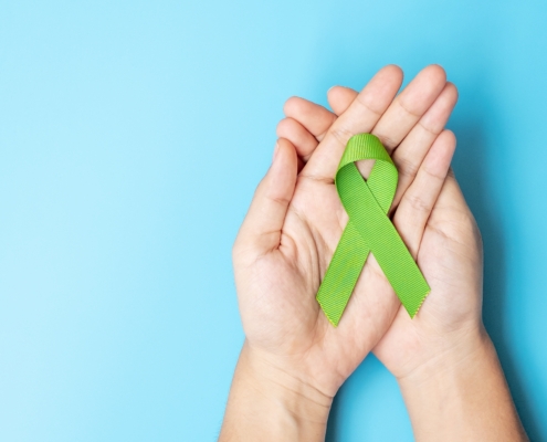 Hand holding a green ribbon for mental health blog cover