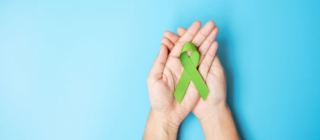 Hand holding a green ribbon for mental health blog cover